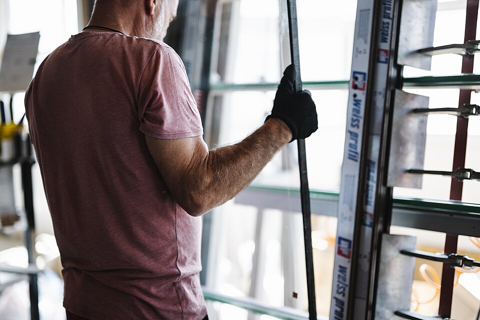 Profissional a manusear um painel de vidro para instalação